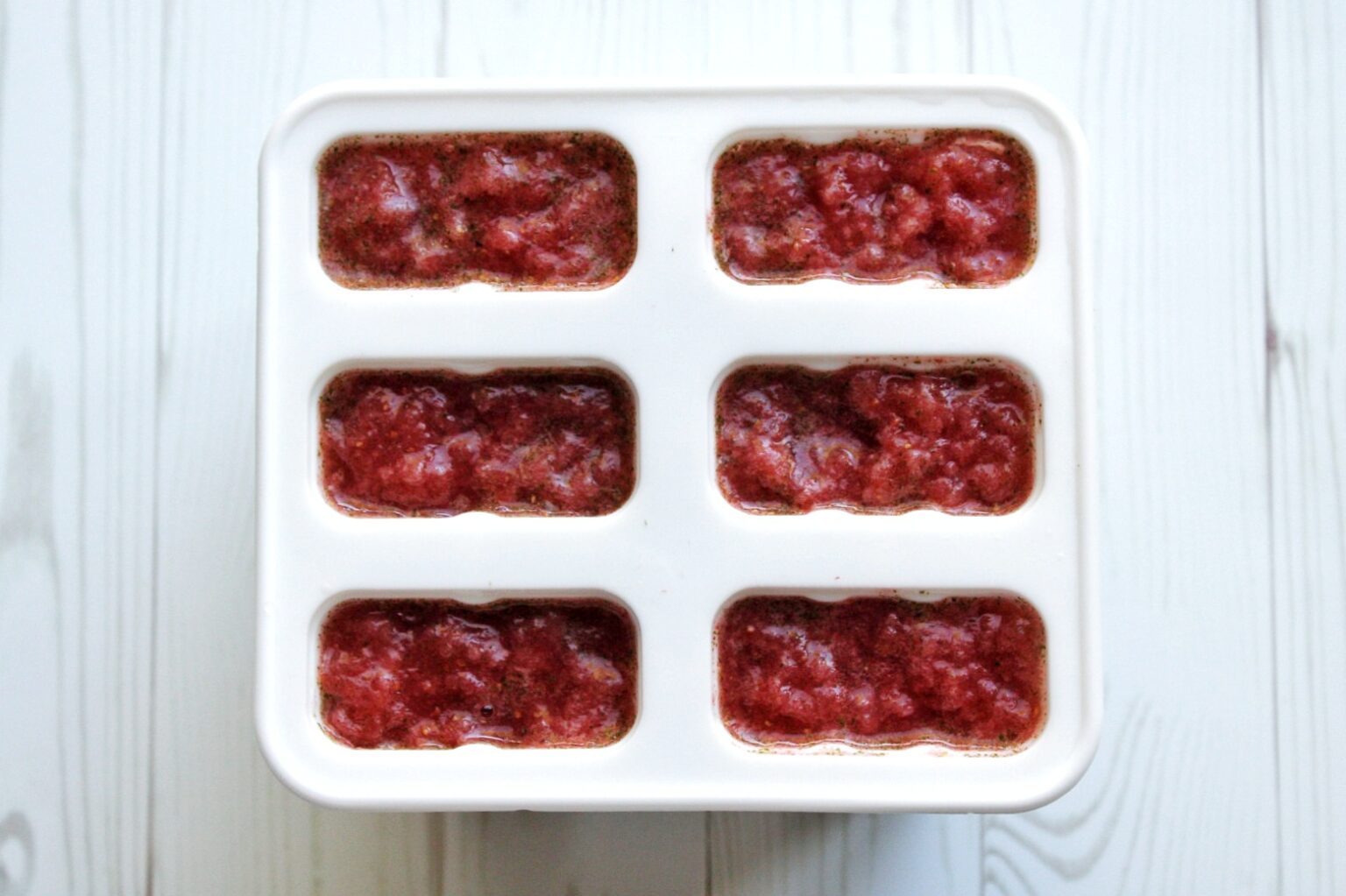 Blended strawberry mint mixture in popsicle mold. 