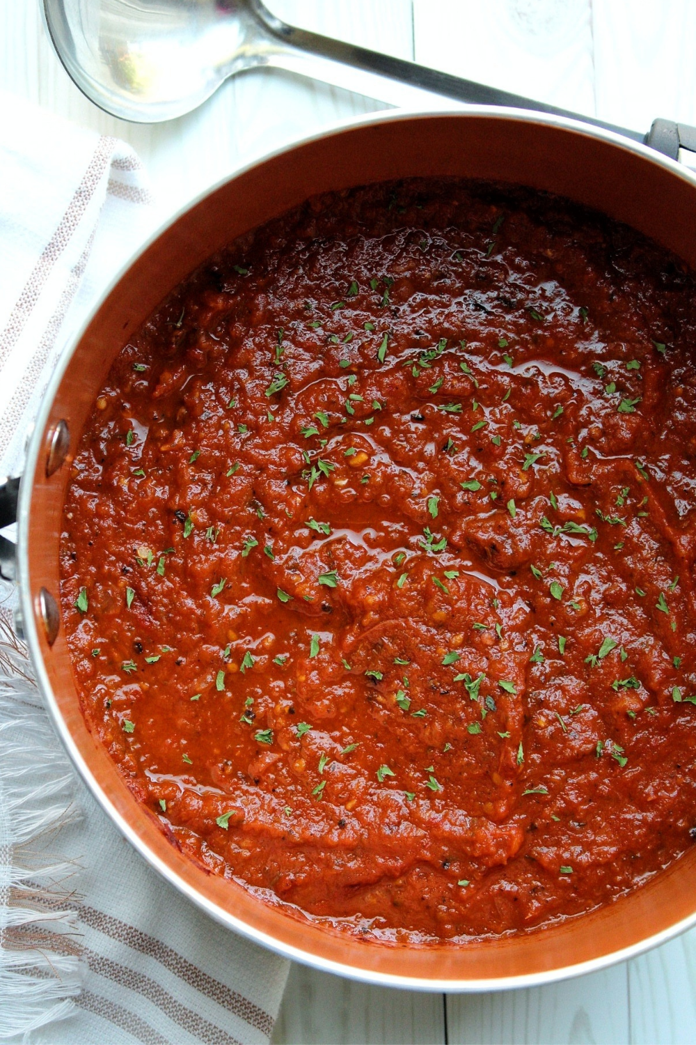 Homemade spaghetti sauce in a saucepan topped with parsley.