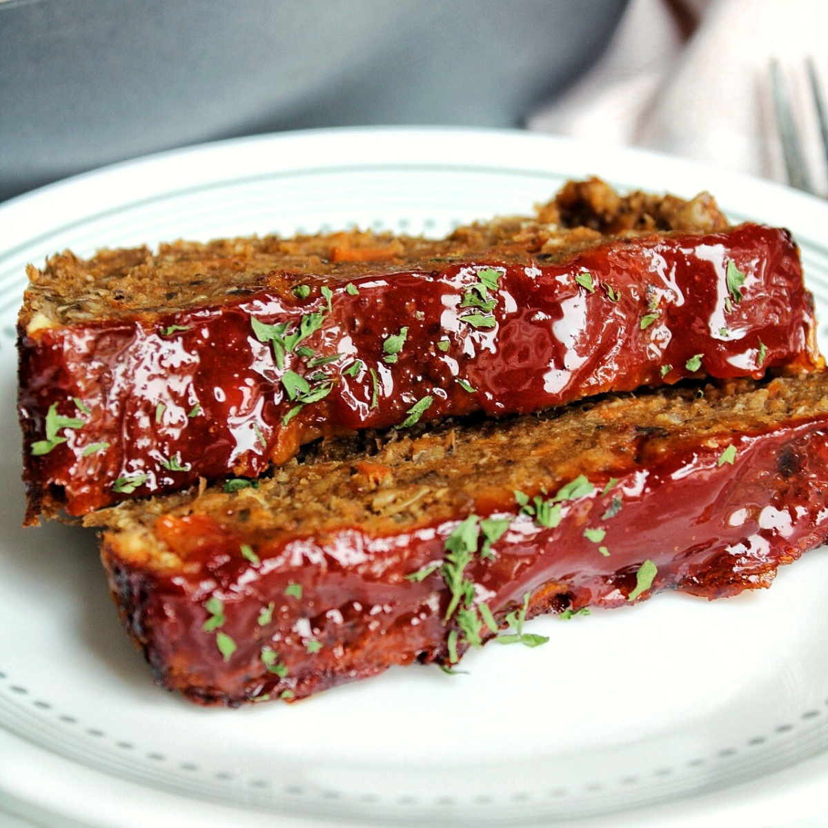 Sliced mushroom lentil loaf with glaze and topped with parsley.