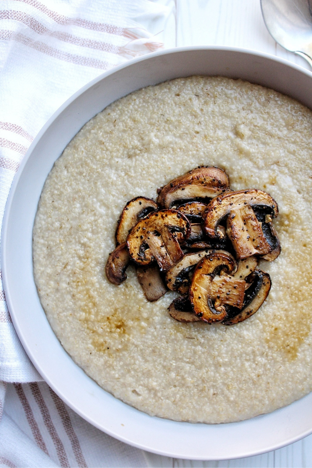 Oat bran in a gray bowl topped with sliced mushrooms and a slice of soy sauce. 