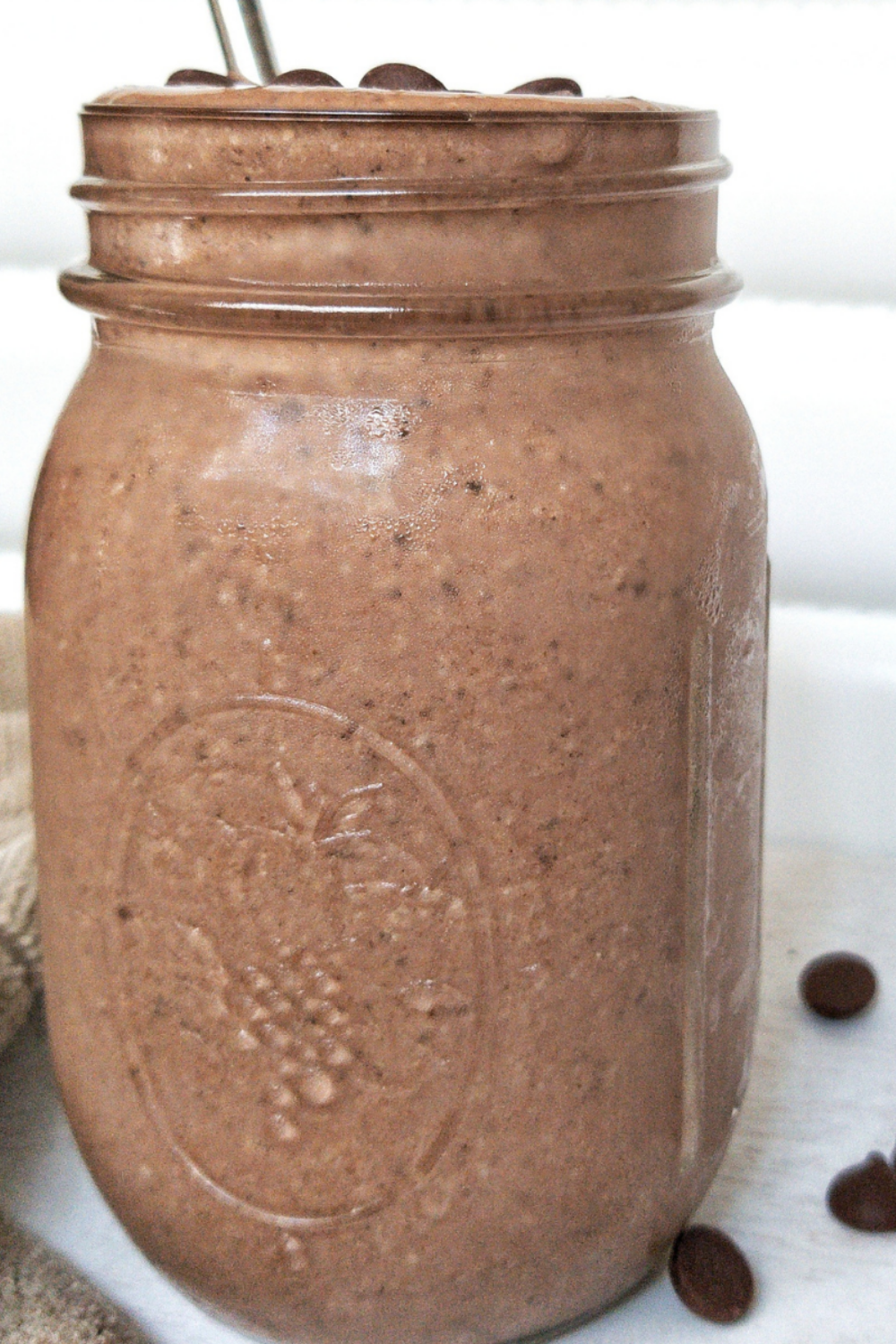 Chocolate peanut butter smoothie in a mason jar with a metal straw 