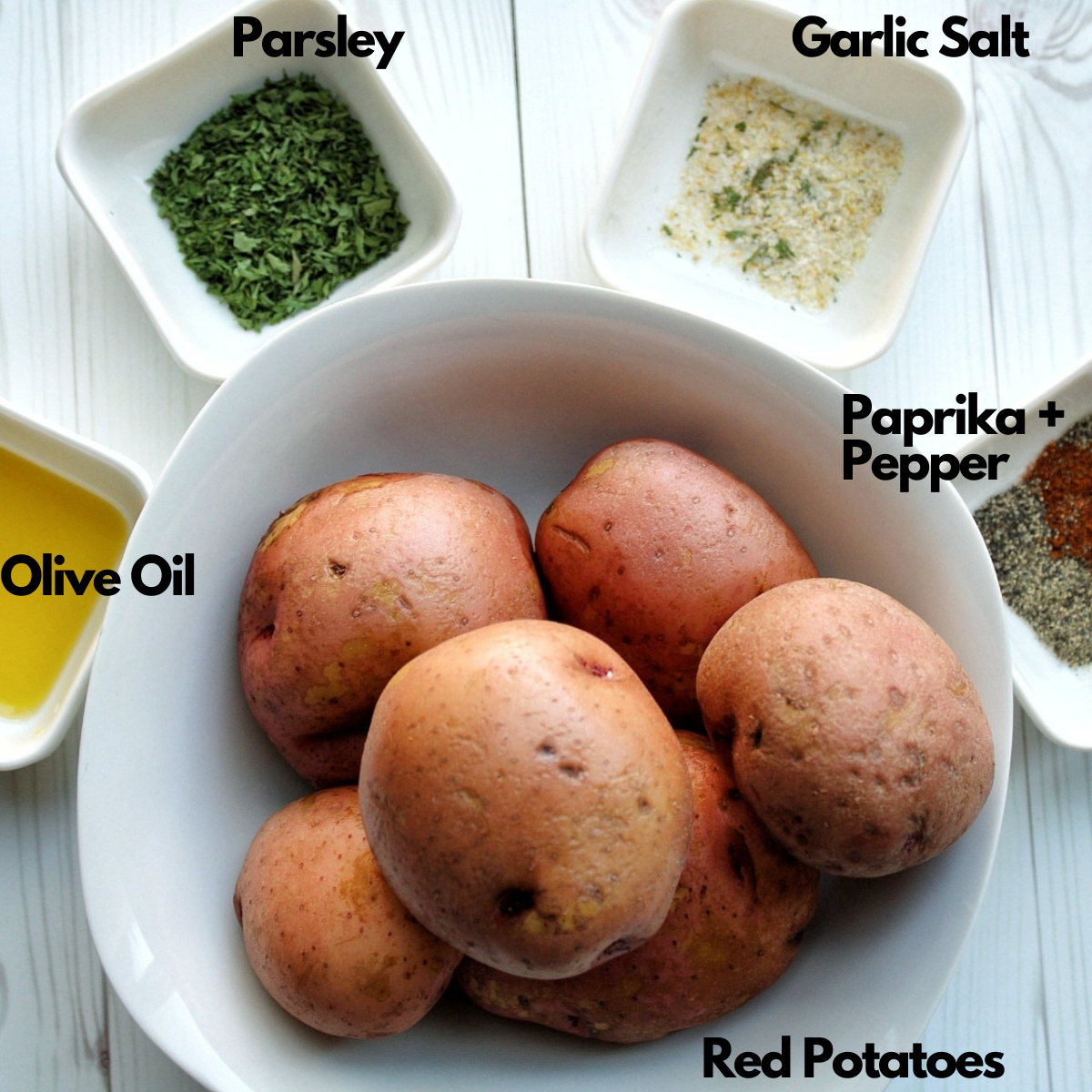 Washed red potatoes in a bowl with olive oil, parsley, garlic salt, black pepper, and paprika 