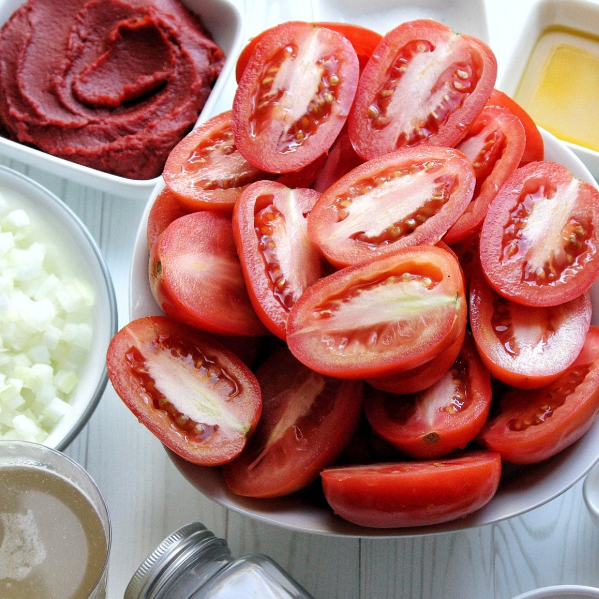 Close up of Roma tomatoes cut in halves along with other ingredients.