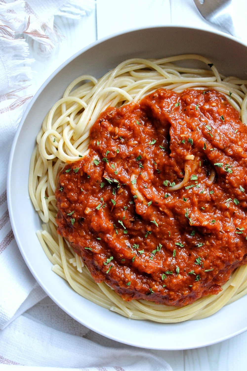 Bowl of spaghetti topped with homemade spaghetti sauce garnished with parsley.