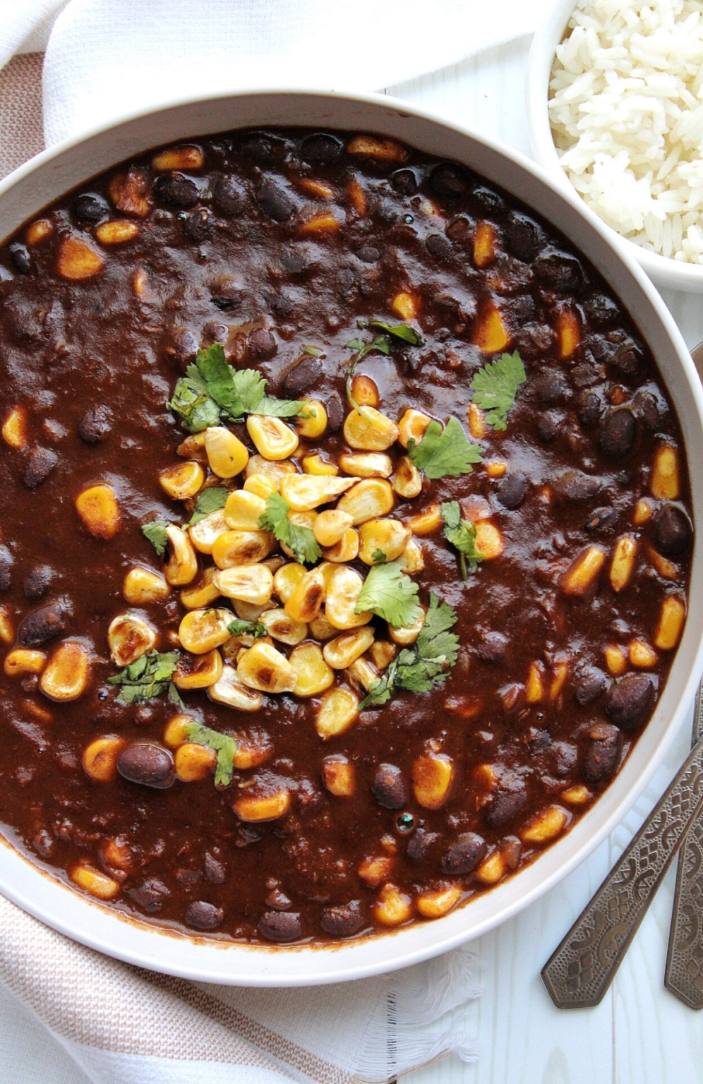 Vegetarian black bean chili with corn and a side of cooked white rice.