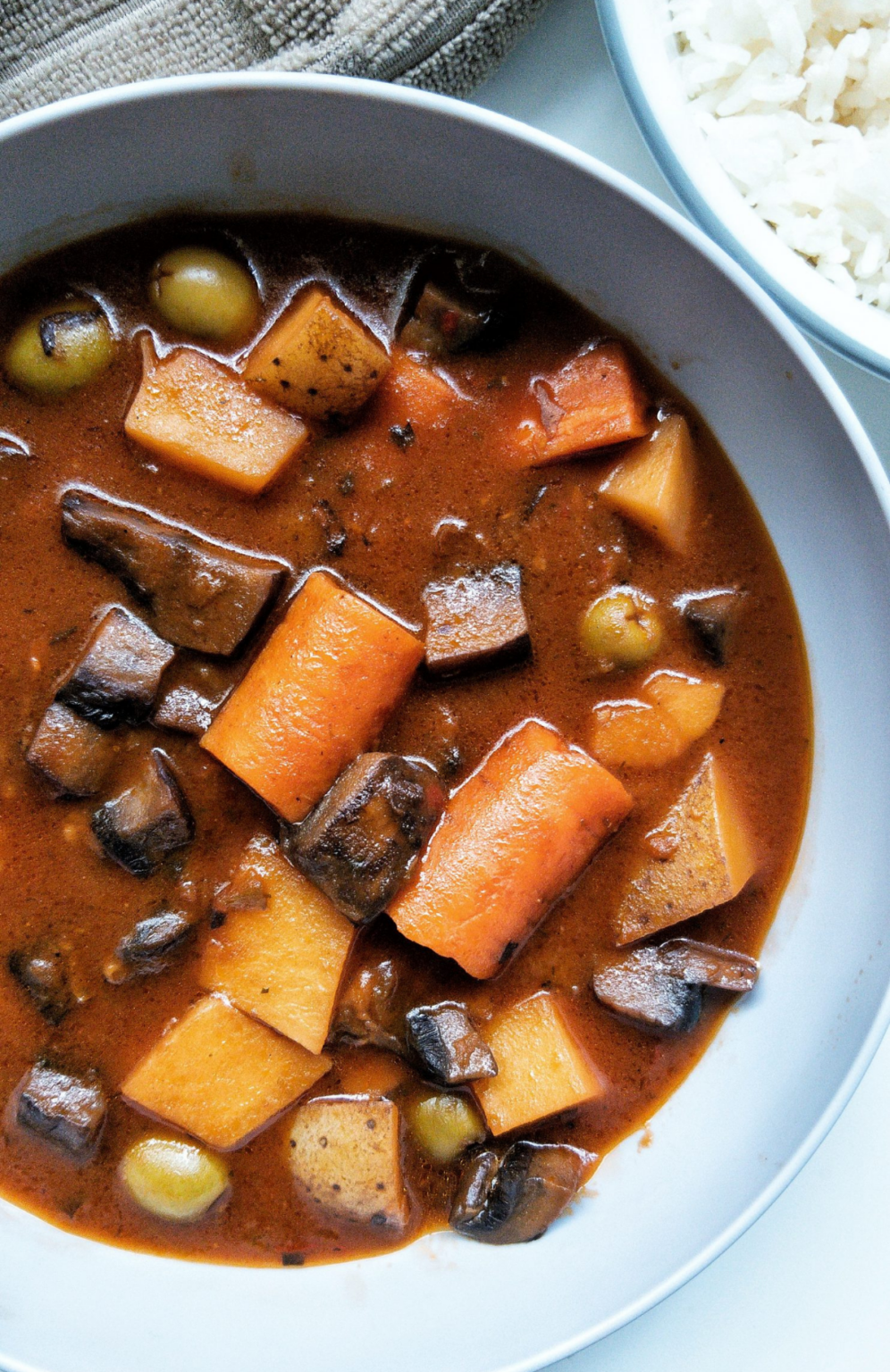 Bowl of plant-based beef stew with mushrooms, carrots, and potatoes. 