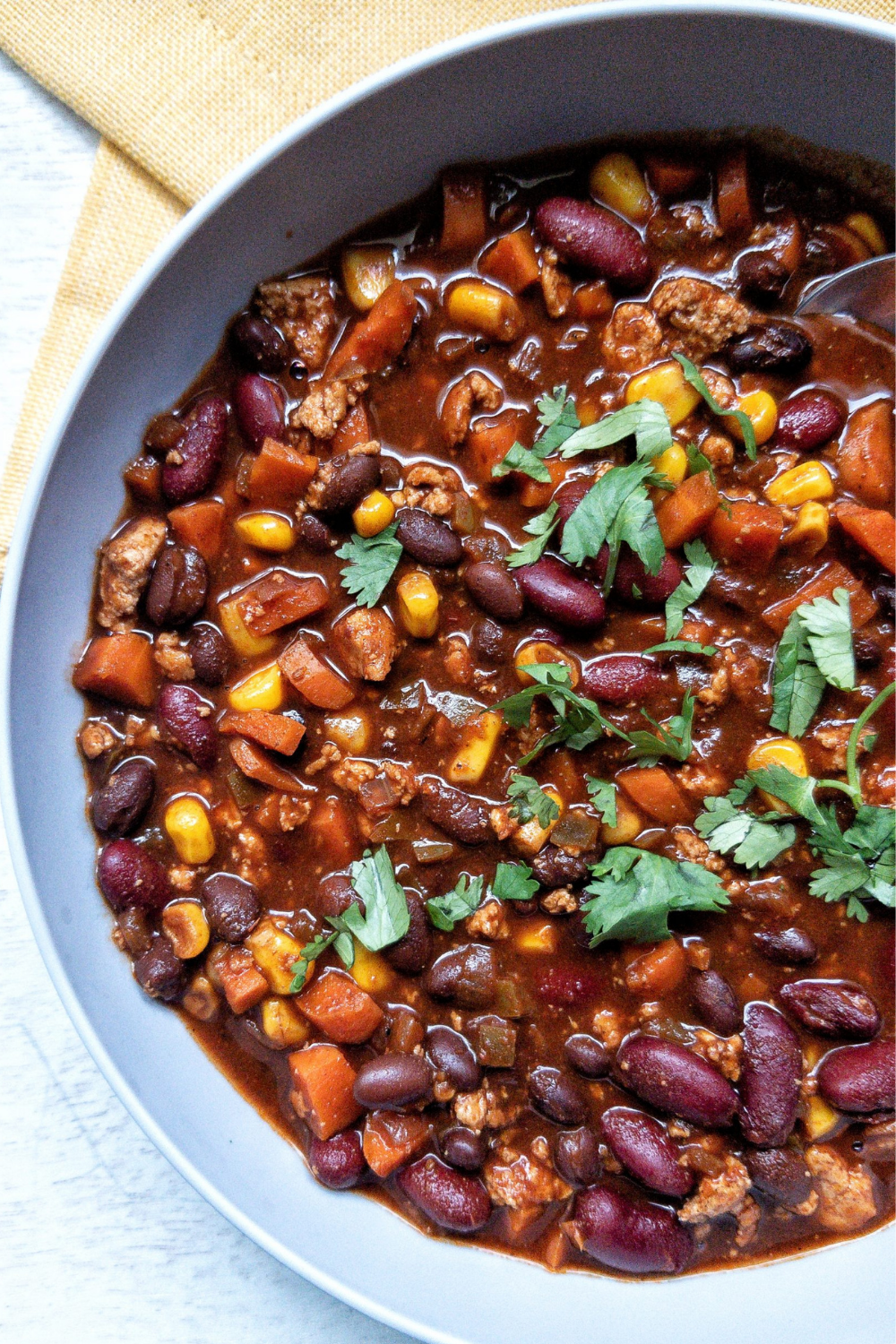 Close up of vegetarian chili with beans tofu, mushrooms, corn, and topped with chopped cilantro 