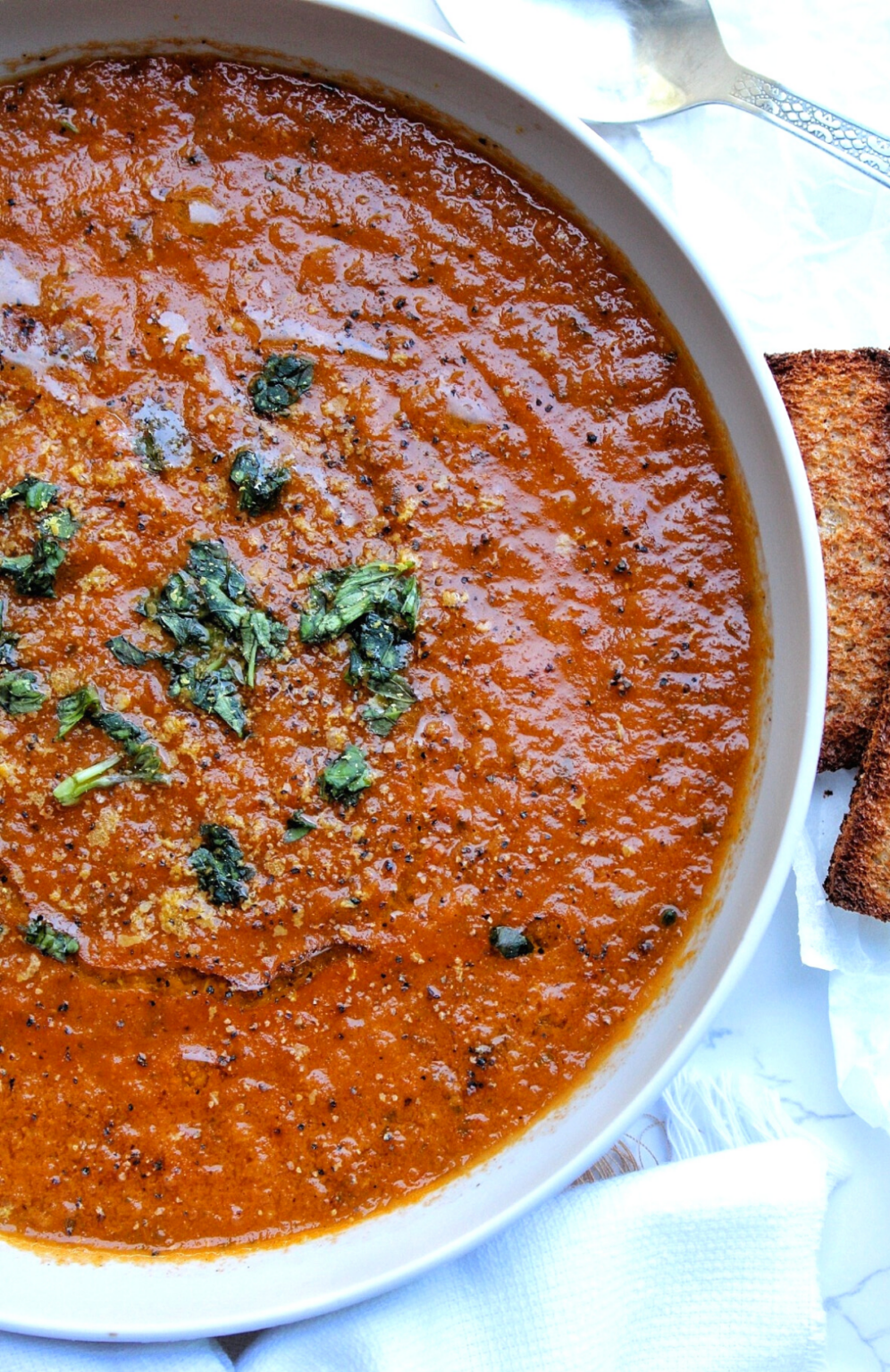 Homemade roasted tomato soup served with choppedbasil and toasted bread. 