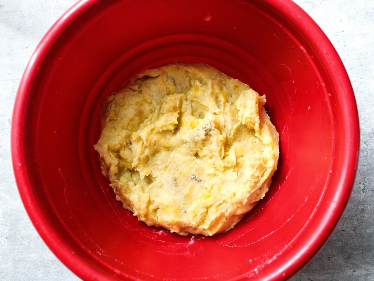 Mashed sweet plantains in a red mixing bowl. 