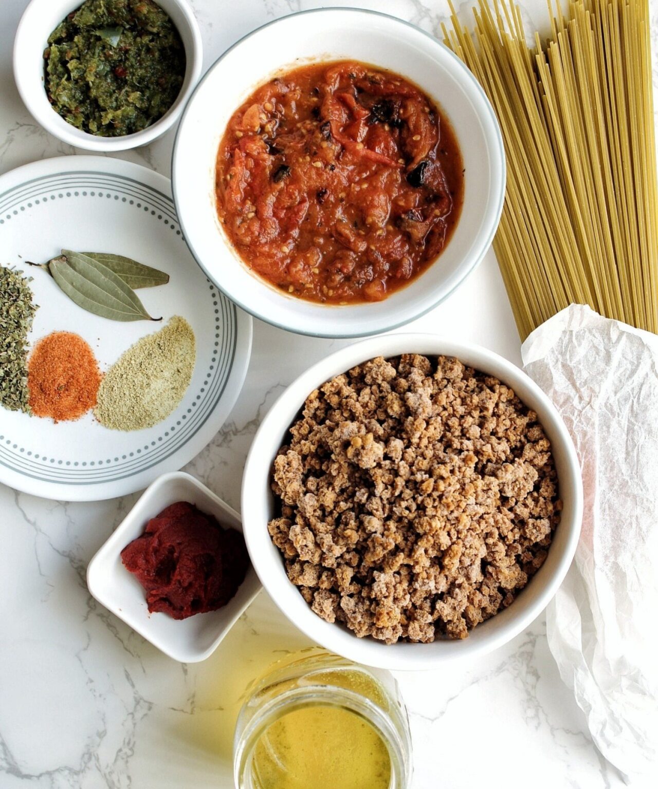 Sofrito, crushed tomatoes, spaghetti, bay leaves, sazon, adobo, oregano, vegan ground beef, tomato paste, vegetable broth. 