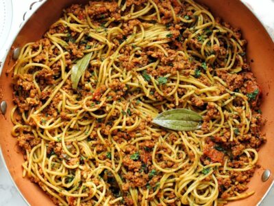 Finished Puerto Rican spaghetti in a large pot with bay leaves.