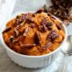 Mashed sweet potatoes in a white serving bowl, topped with toasted chopped walnuts.