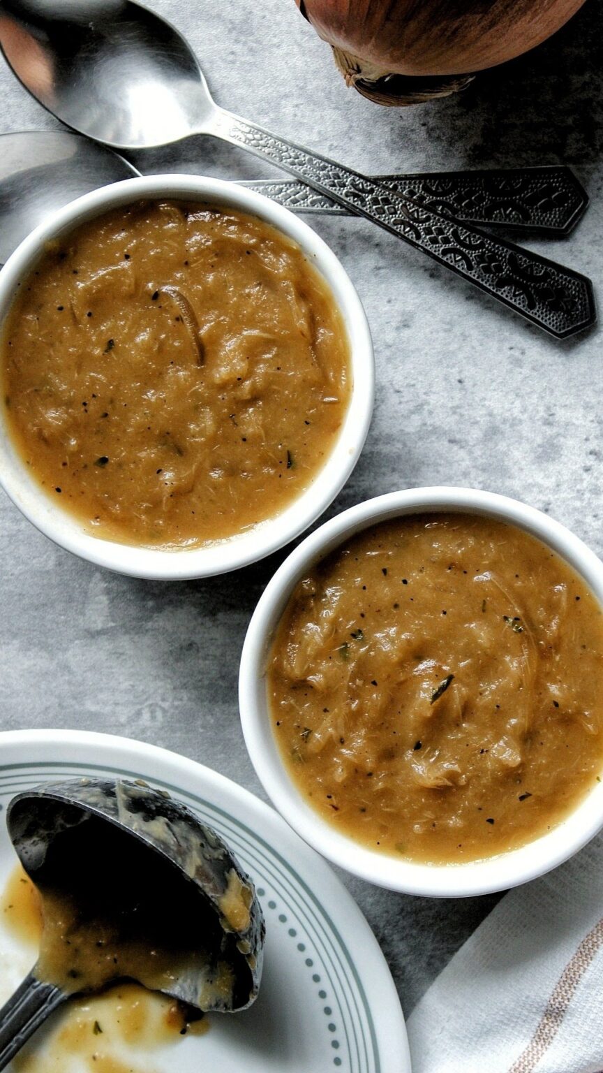 Onion gravy in two small white jars with spoons. 