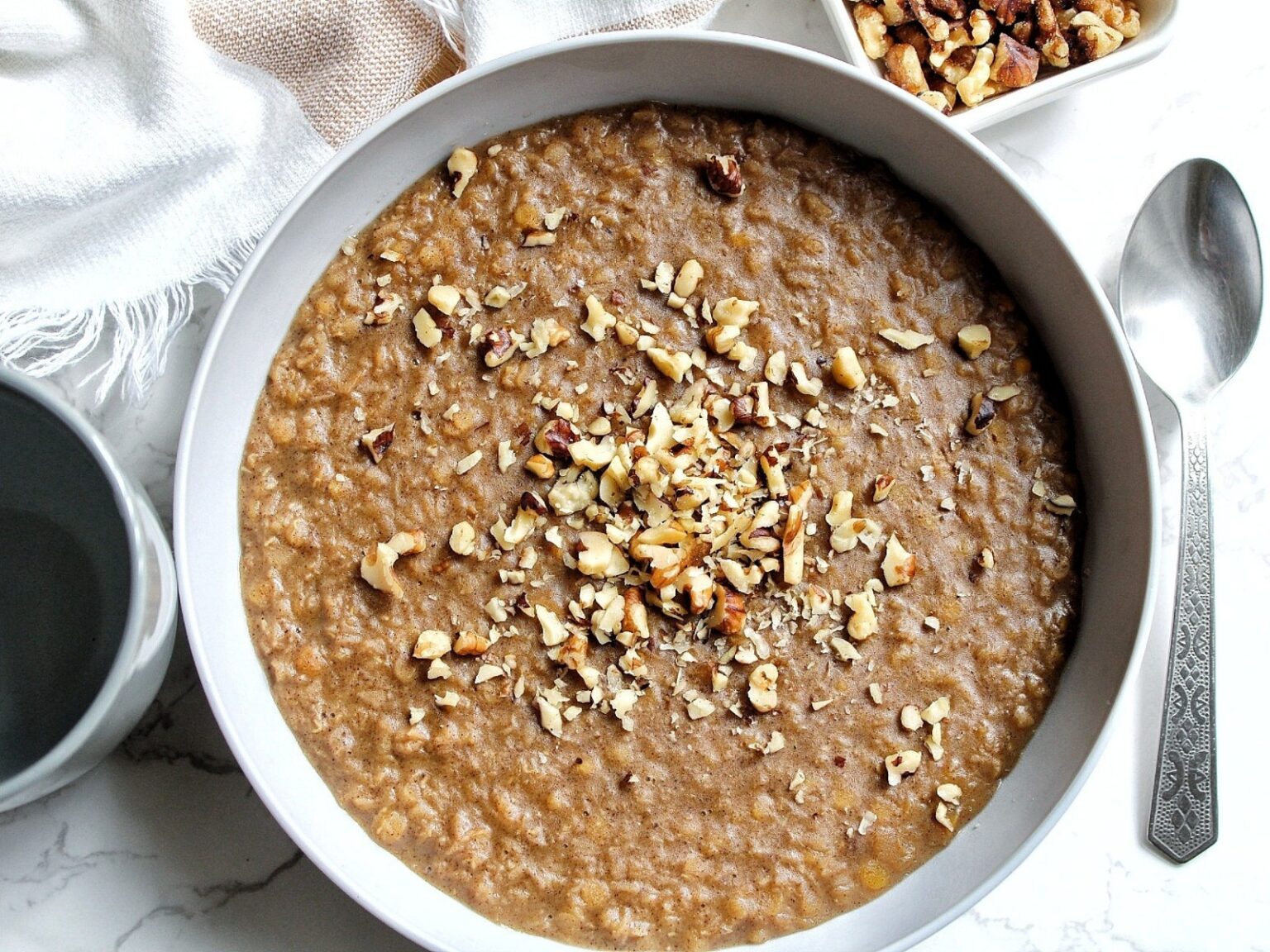 A bowl of cooked red split lentils topped with chopped walnuts in a gray bowl.