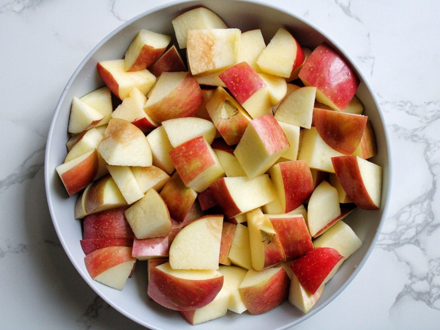 Gray bowl with chopped fuji apples.