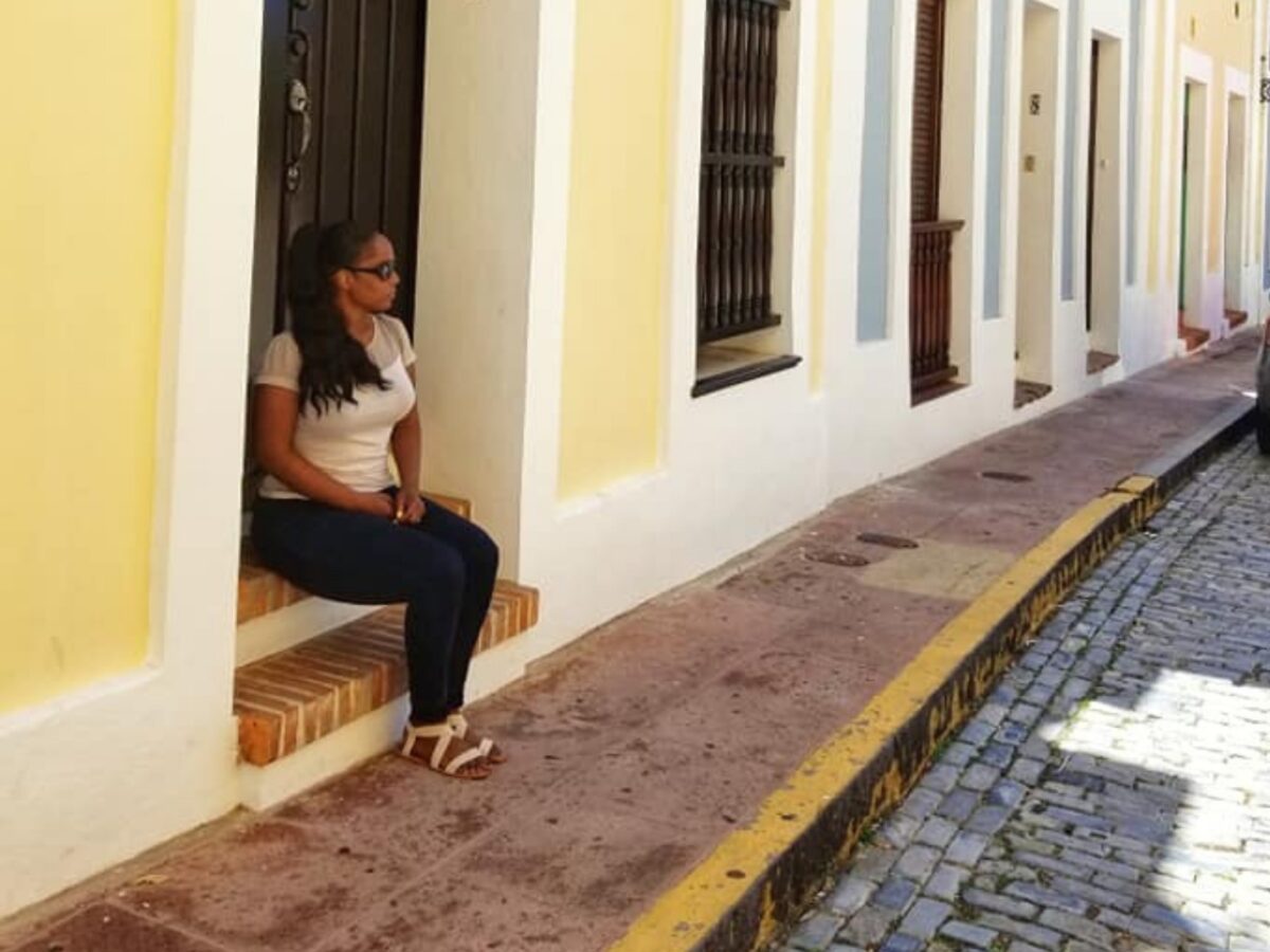 Aly in Puerto Rico sitting on a couple of steps outside of residential buildings. 