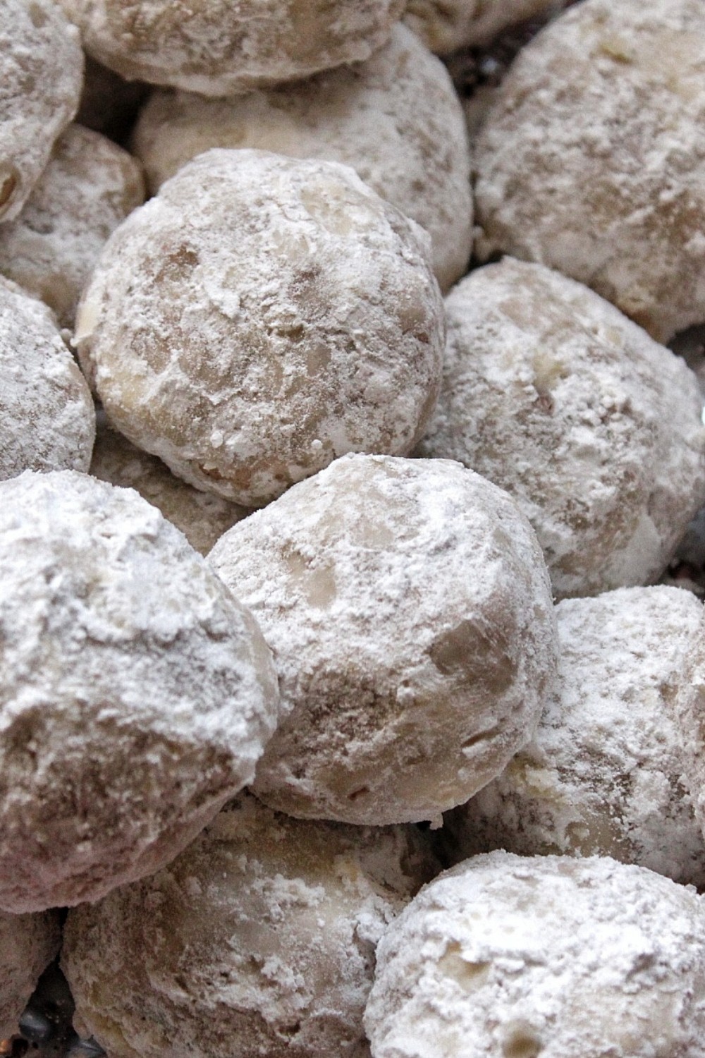 Snowball cookies covered in powdered sugar up close. 