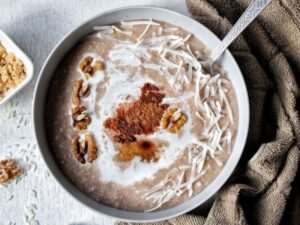 Homemade cream of rice in a gray bowl topped with a splash of coconut milk, nuts, cinamon, and cinnamon flakes.