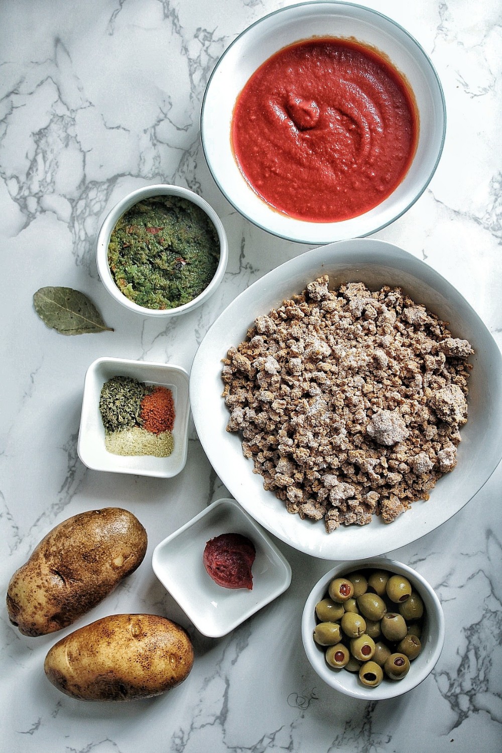 Tomato sauce, tomato paste, sofrito, bay leaf, frozen ground beef, potatoes, Spanish green olives, and spices.