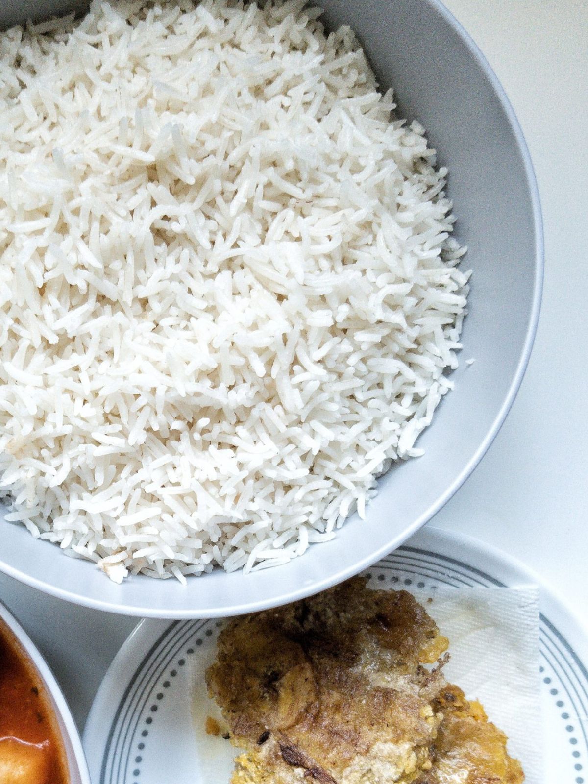 Bowl of white rice with fried green plantains (tostones) on the side.