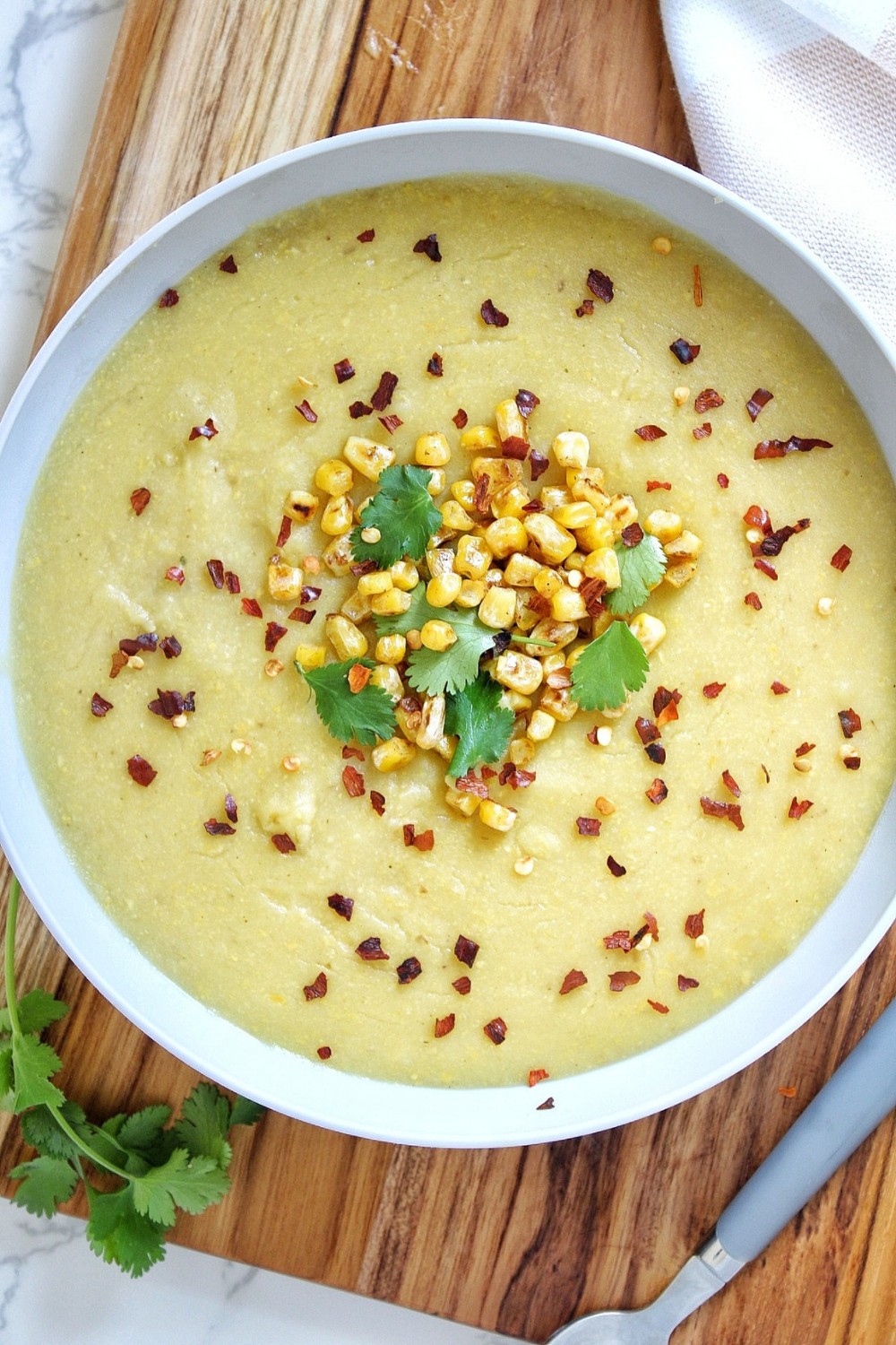 Chopped cilantro, roasted corn, and crushed red pepper topped over corn soup.