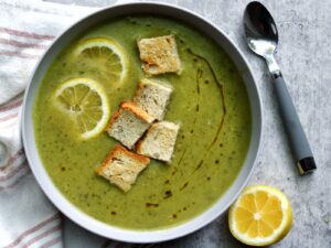 Zucchini soup in a bowl topped with lemon slices and homemade croutons.