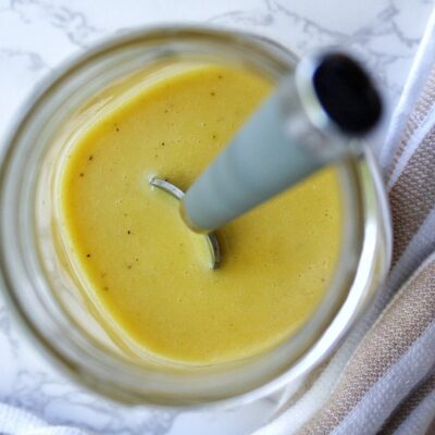 Homemade apple cider vinaigrette salad dressing in a mason jar with a spoon.