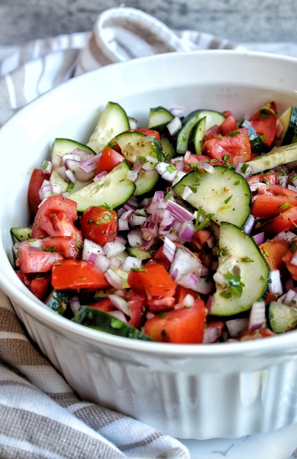 Chopped vegetable salad with cucumbers, tomatoes, onion, parsley, and dressing.