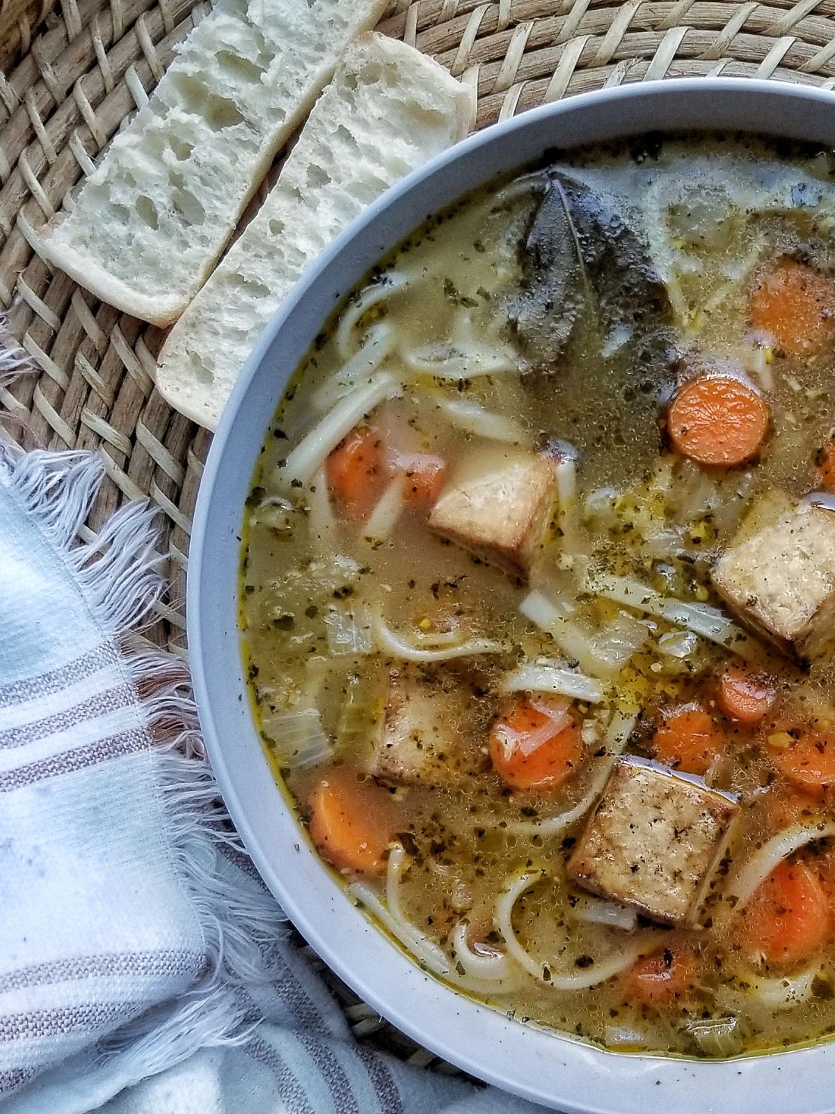 Vegan “Chicken” Noodle Soup with Tofu in a bowl served with fresh bread.