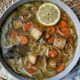Vegan chicken noodle soup in a bowl with a slice of lemon.