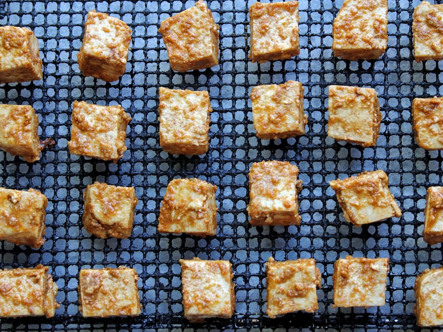 Tofu cubes on an air fryer tray.