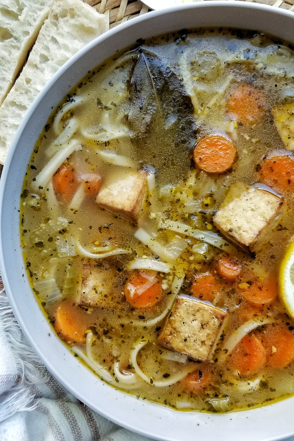 Close-up of soup with carrots, tofu, vegetables, and noodles.