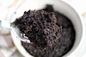 Vegan chocolate cake in a mug with a spoon.