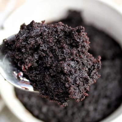 Vegan chocolate cake in a mug with a spoon.