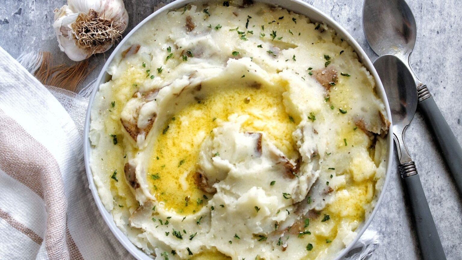 Bowl of buttery mashed potatoes topped with dried herbs. 