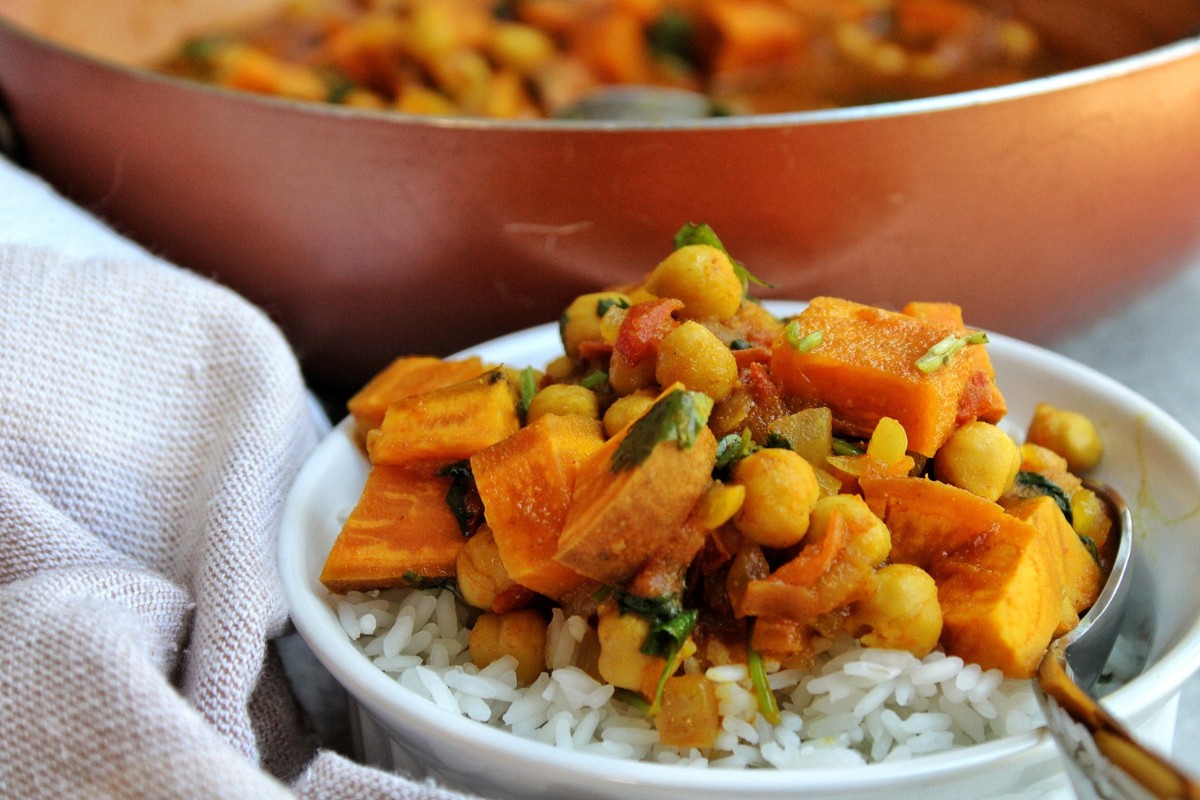 Bowl of sweet potato curry with white rice and a serving spoon. 