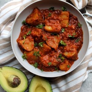 Stewed potatoes in tomato sauce, topped with chopped cilantro.