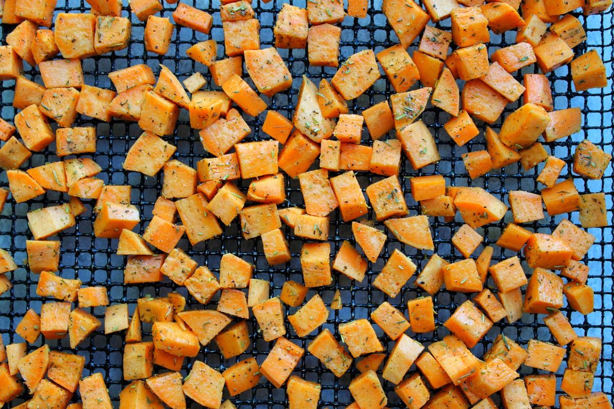 Chopped, raw sweet potato cubes on an air fryer rack. 