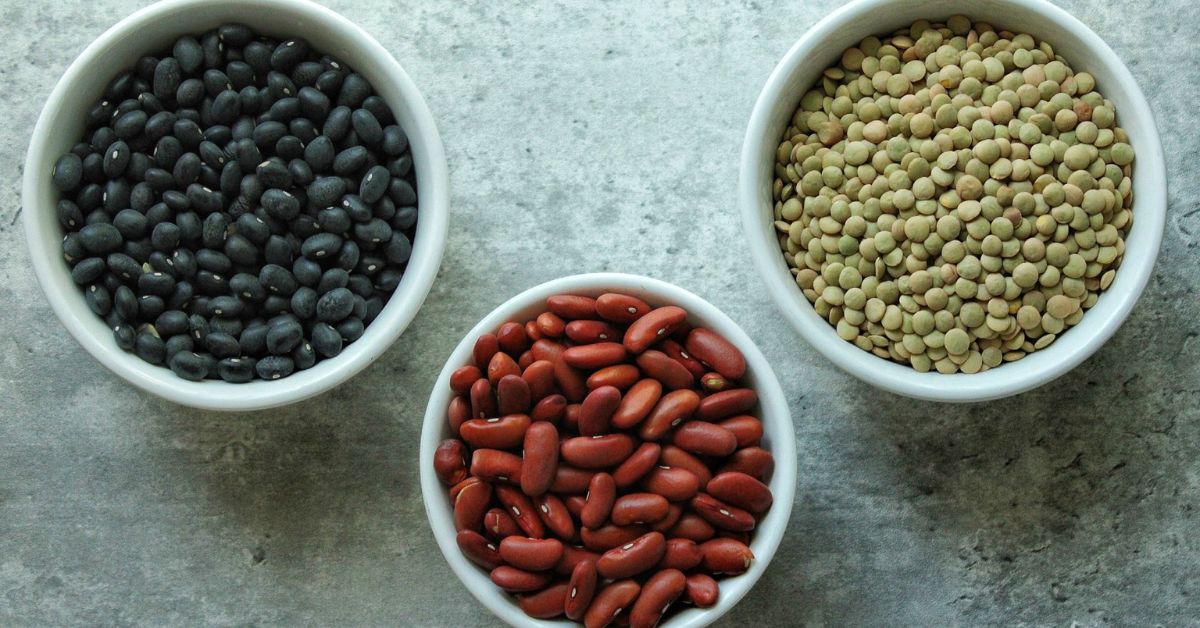 Black Beans, red kidney beans, and green lentils in 3 separate white bowls.