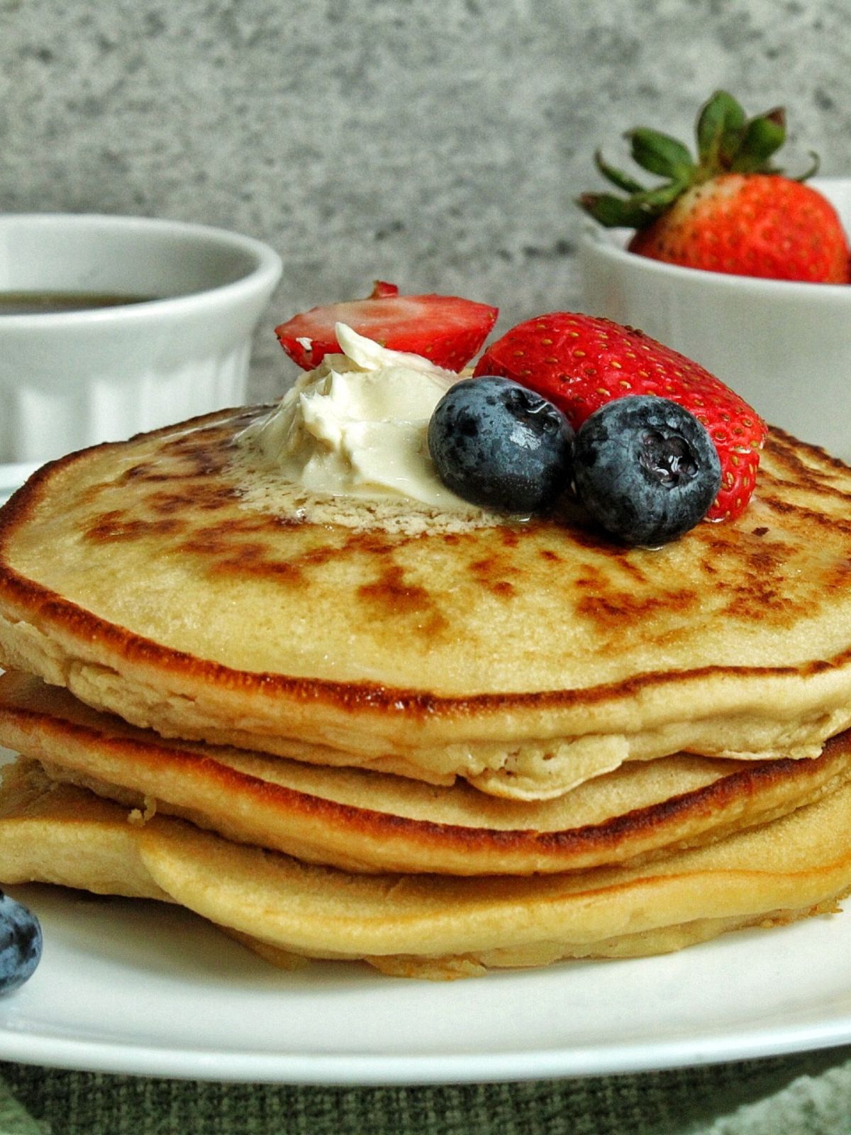 Whole wheat pancakes with blueberries and strawberries and a dollop of butter. 