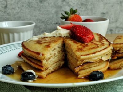 Stack of whole wheat pancakes topped with strawberries and blueberries.