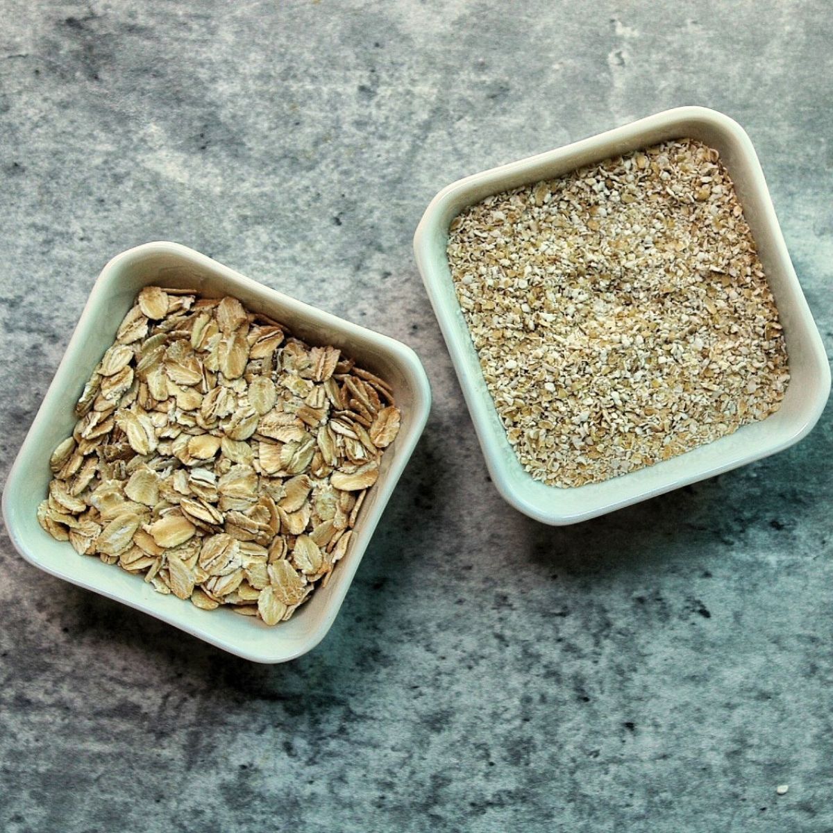 Raw rolled oats and oat bran in white, glass containers.