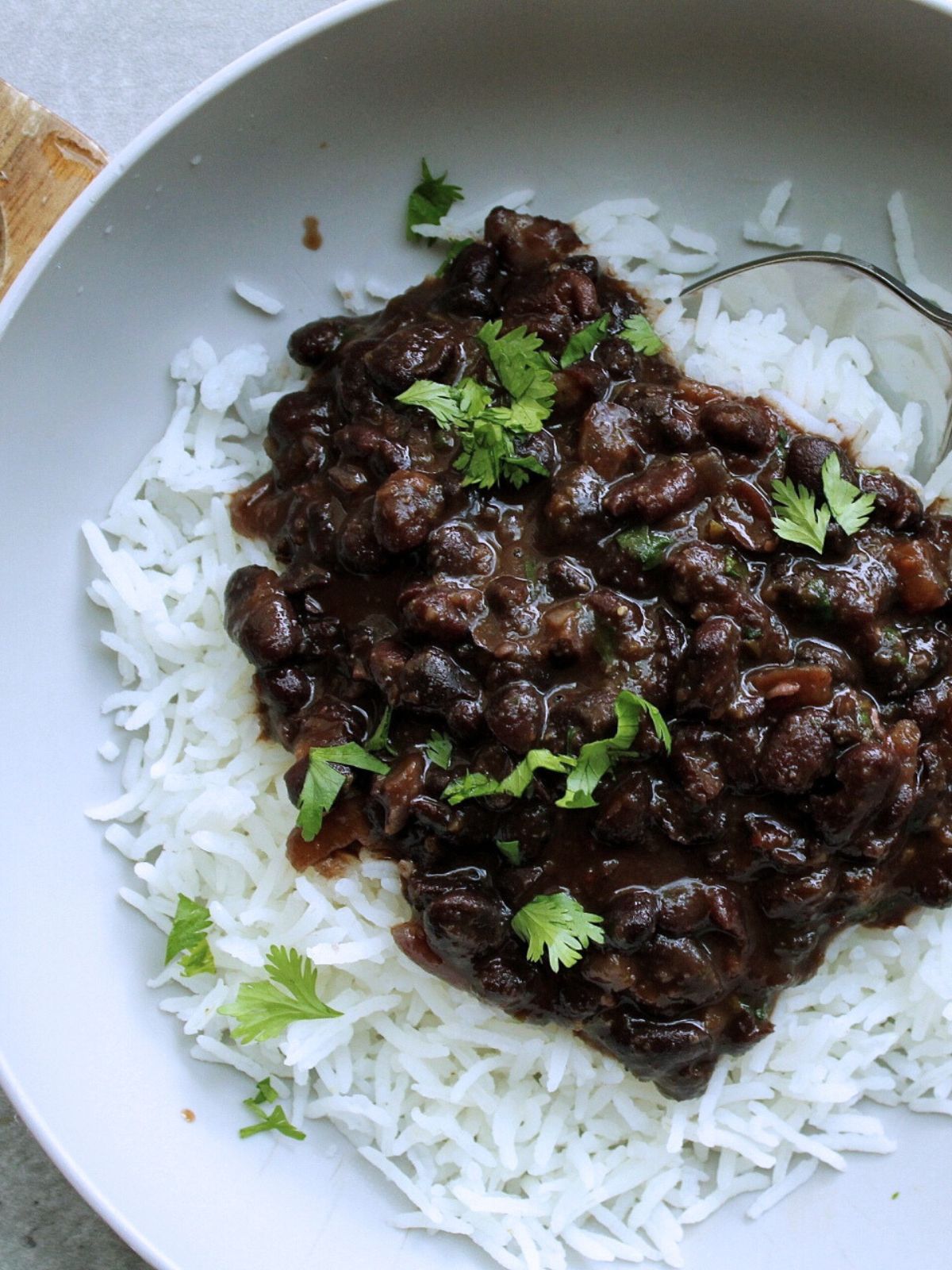 Bowl of rice with pressure cooker black beans topped with chopped cilantro, closeup. 