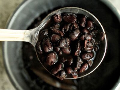 A scoop of saucy black beans from a pressure cooker.