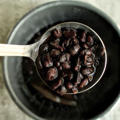 A scoop of saucy black beans from a pressure cooker.