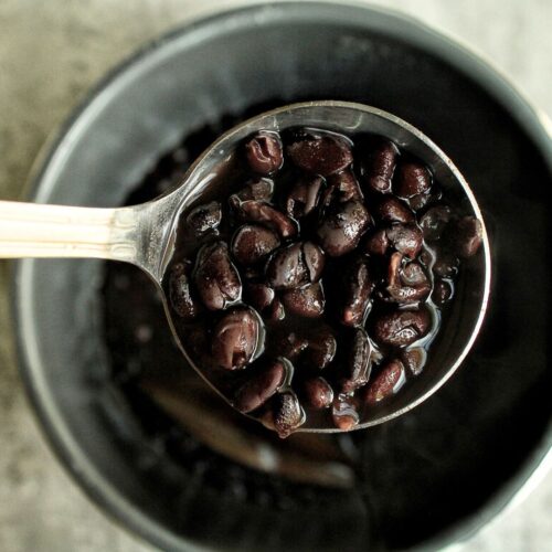 A scoop of saucy black beans from a pressure cooker.