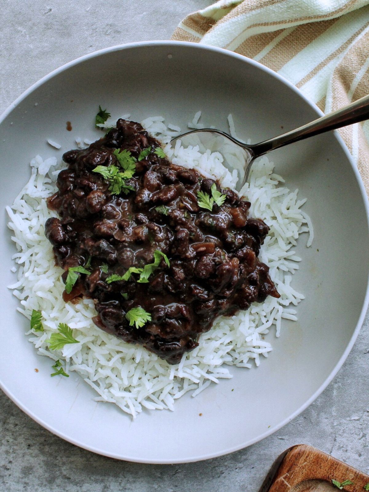 A bowl of white rice topped with creamy black beans and chopped cilantro. 