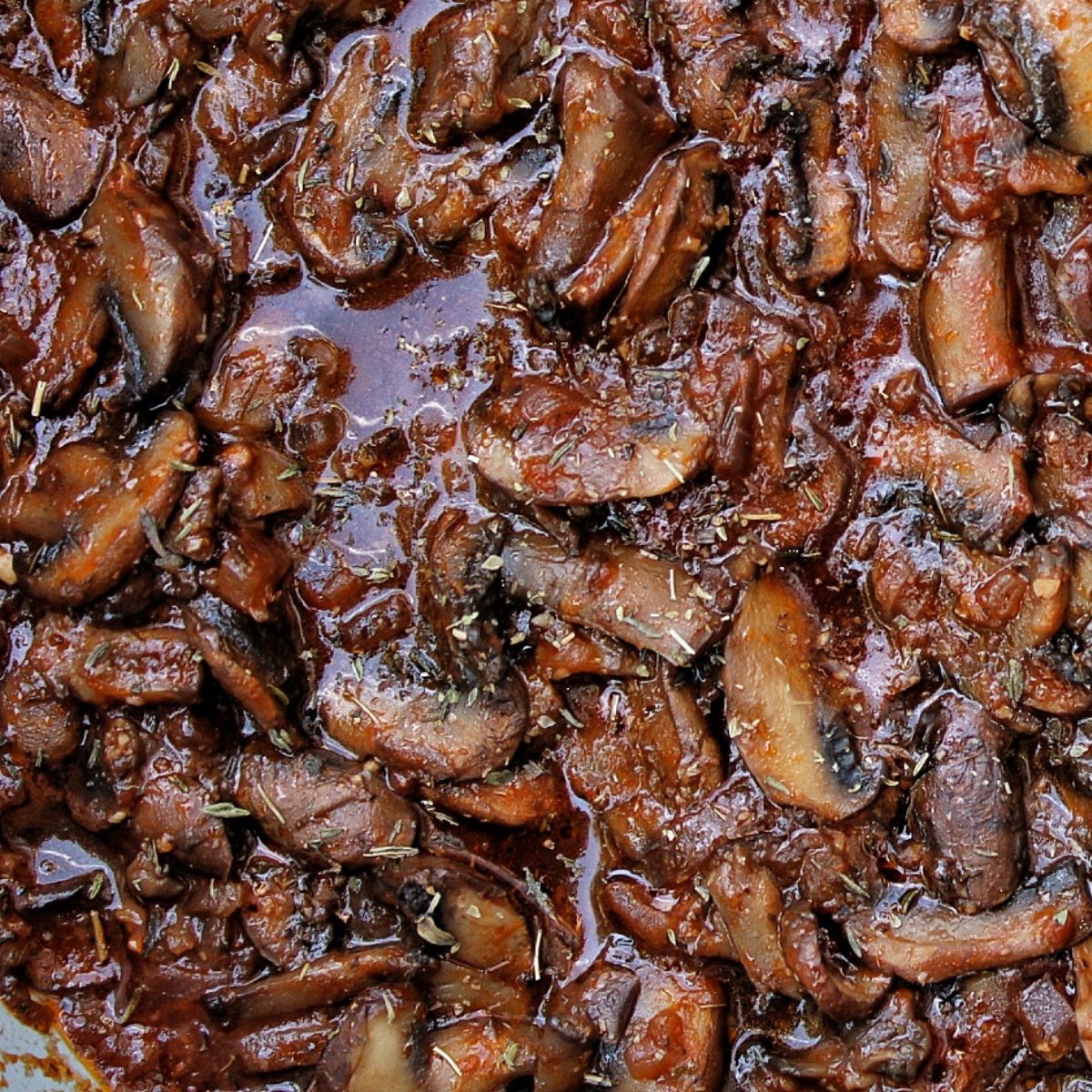 Closeup of cooked mushrooms in a sauce.